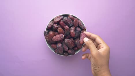 Hand-pick-a-dried-date-fruit-from-a-bowl