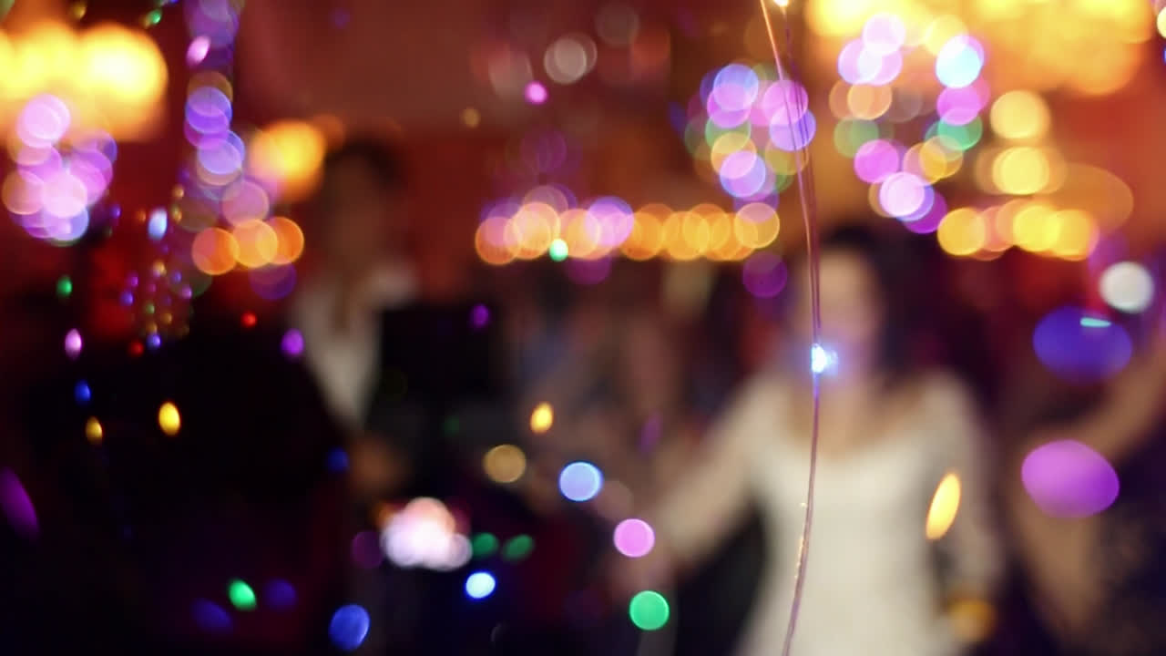 Walking with glowing led balloon over camera lens, unrecognizable bride in background