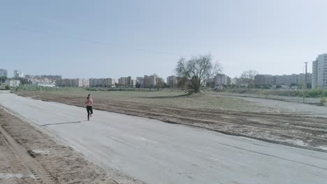 dron giratorio amplio plano de joven morena fitness mujer corriendo en el camino de la dieta del parque urbano