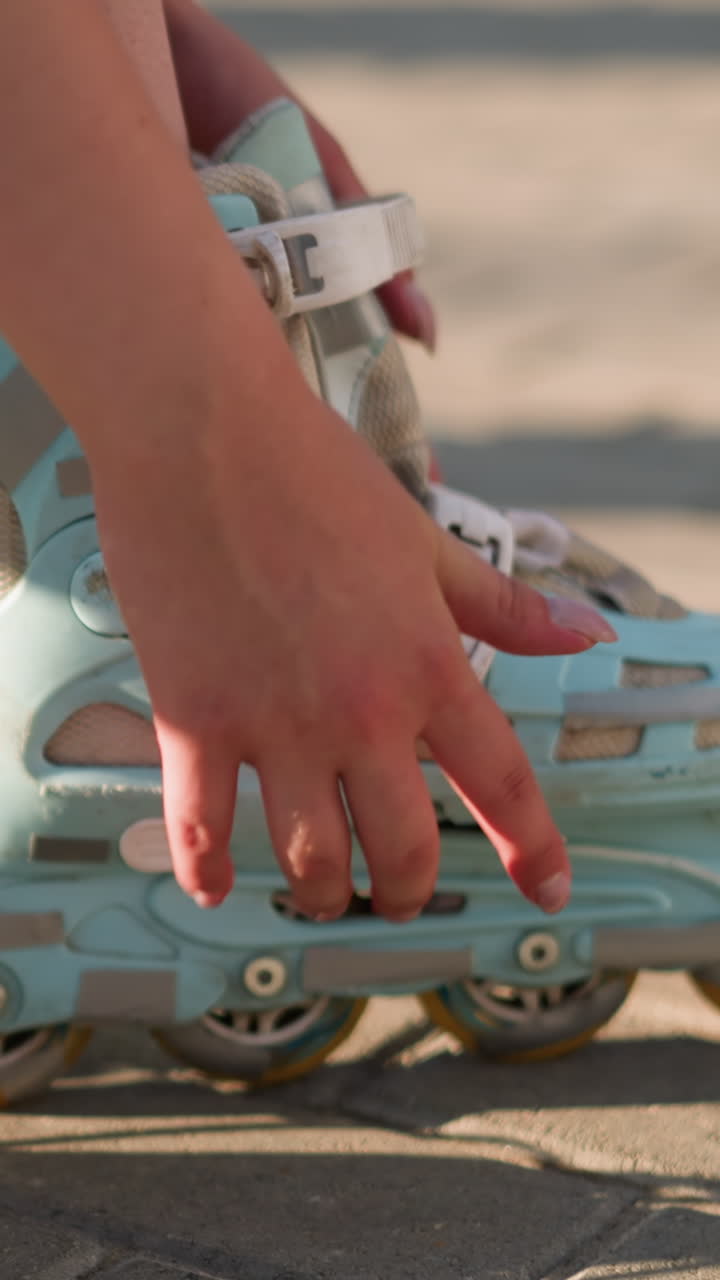 Side view of individual adjusting strap on roller skate of left leg, ensuring secure fit, hand focusing on buckle under sunlight, with slight movement, partially visible white sneakers