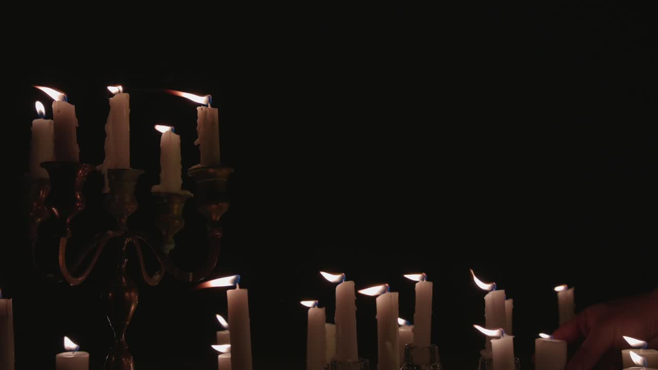 un grupo de velas blancas, algunas en un candelabro, encendidas y funcionando durante un tiempo