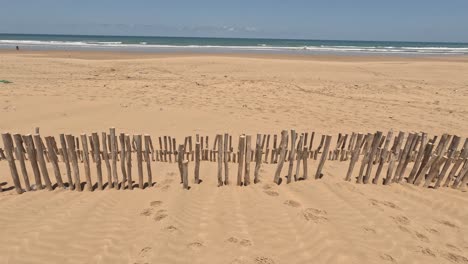 Natürlicher-Und-Wilder-Strand-Mit-Einem-Schönen-Und-Ausgedehnten-Dünengebiet,-Das-Mit-Reihen-Und-Holzlinien-Geschützt-Ist