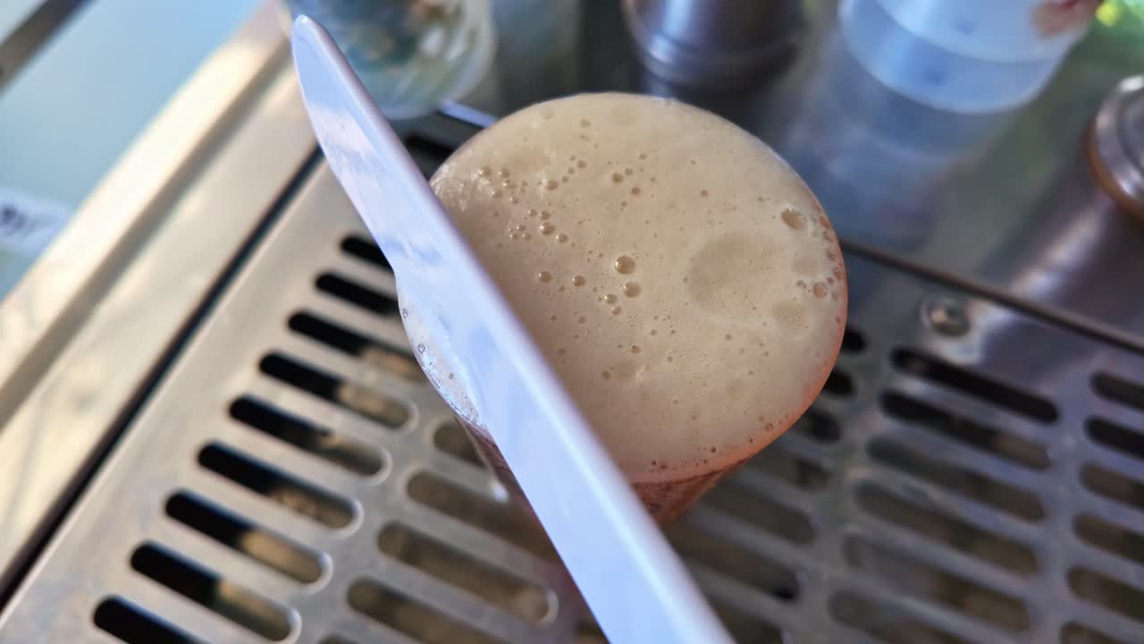 Primo piano di un bicchiere di birra pieno e rimozione della sua schiuma con uno strumento appropriato, Francia.