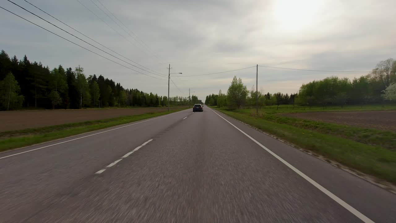 자동차 가 도로 를 따라 미끄러지면서, 다른 차량 들 은 푸른 풍경 으로 둘러싸여 그  ⁇  으로 이동 한다