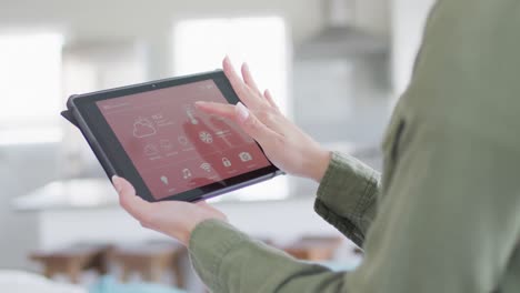 caucasian woman using tablet with smart home interface on screen at home