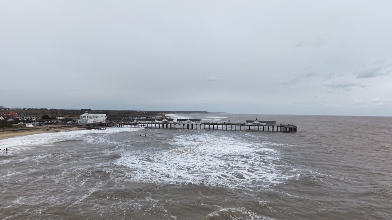 Low Panning drone aerial Southwold Pier in winter rough seas Suffolk UK