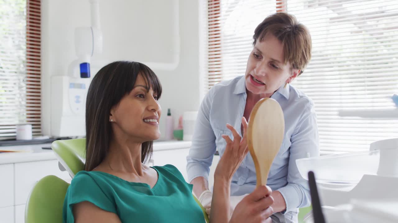 Caucasian female dental nurse talking with female patient at modern dental clinic
