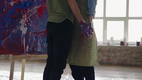 Young-couple-in-love-standing-in-front-their-artwork-and-kissing