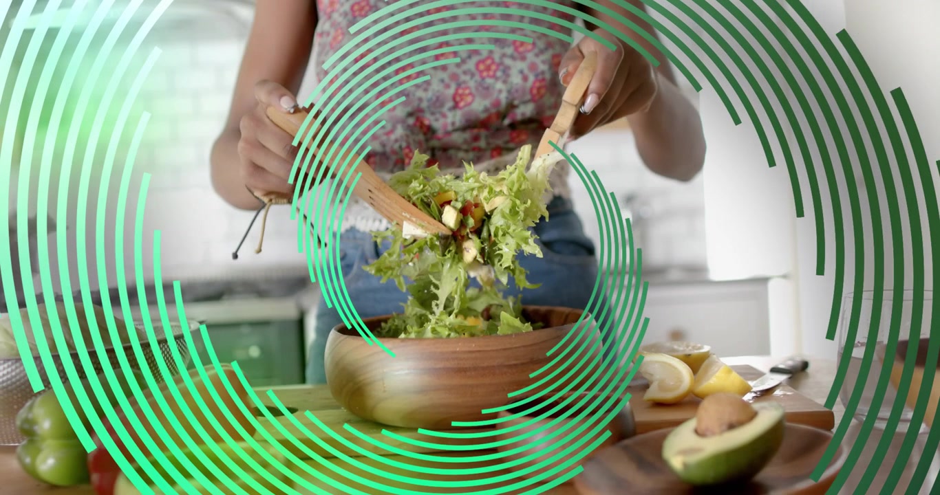 Hjemmekok rækker ud efter træserveringsbestik og vender salat i et moderne køkken for at blande ingredienserne jævnt