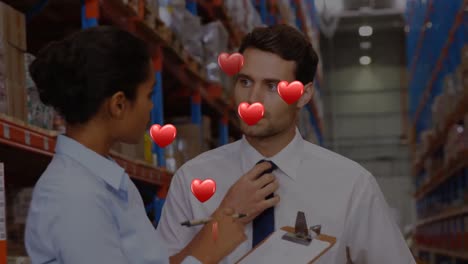 Animation-of-hearts-floating-over-diverse-female-and-male-warehouse-workers-talking