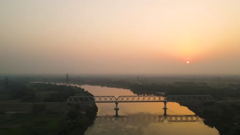 aerial drone view of a tranquil forest and river, bathed in the soft light of sunrise.