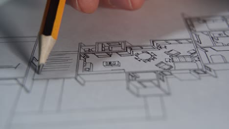 architect draws a house plan, geometric shapes by pencil on sheet of paper at office desk