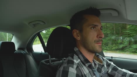 Man-in-black-and-white-shirt-driving-from-a-road-junction,-looks-back