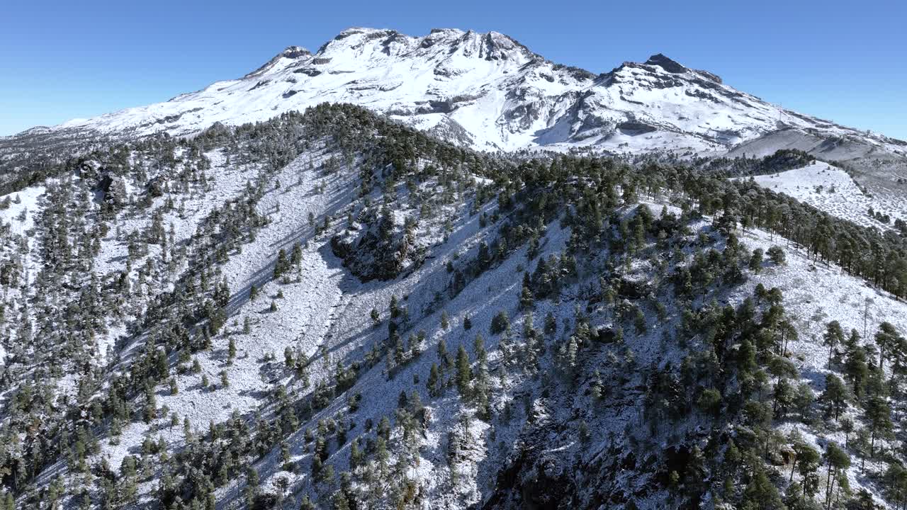 The breathtaking sight of Iztaccihuatl, Mexico, cloaked in rare snow. This captivating aerial video highlights the majestic volcano's winter transformation, ideal for nature and travel projects.