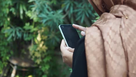 woman in hijab using a smartphone outdoors