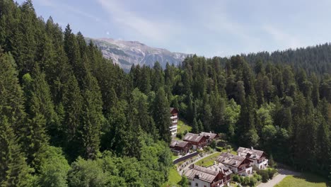 aerial flyover swiss neighborhood of laax a famous city for hiking and skiing. revealing flight showing alps mountain range in distance. sunny summer day