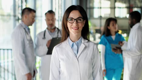 retrato de un hermoso médico con gafas y un vestido blanco, sonriendo a la cámara en una clínica