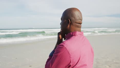 hombre afroamericano caminando por una playa en pensamiento mirando el mar
