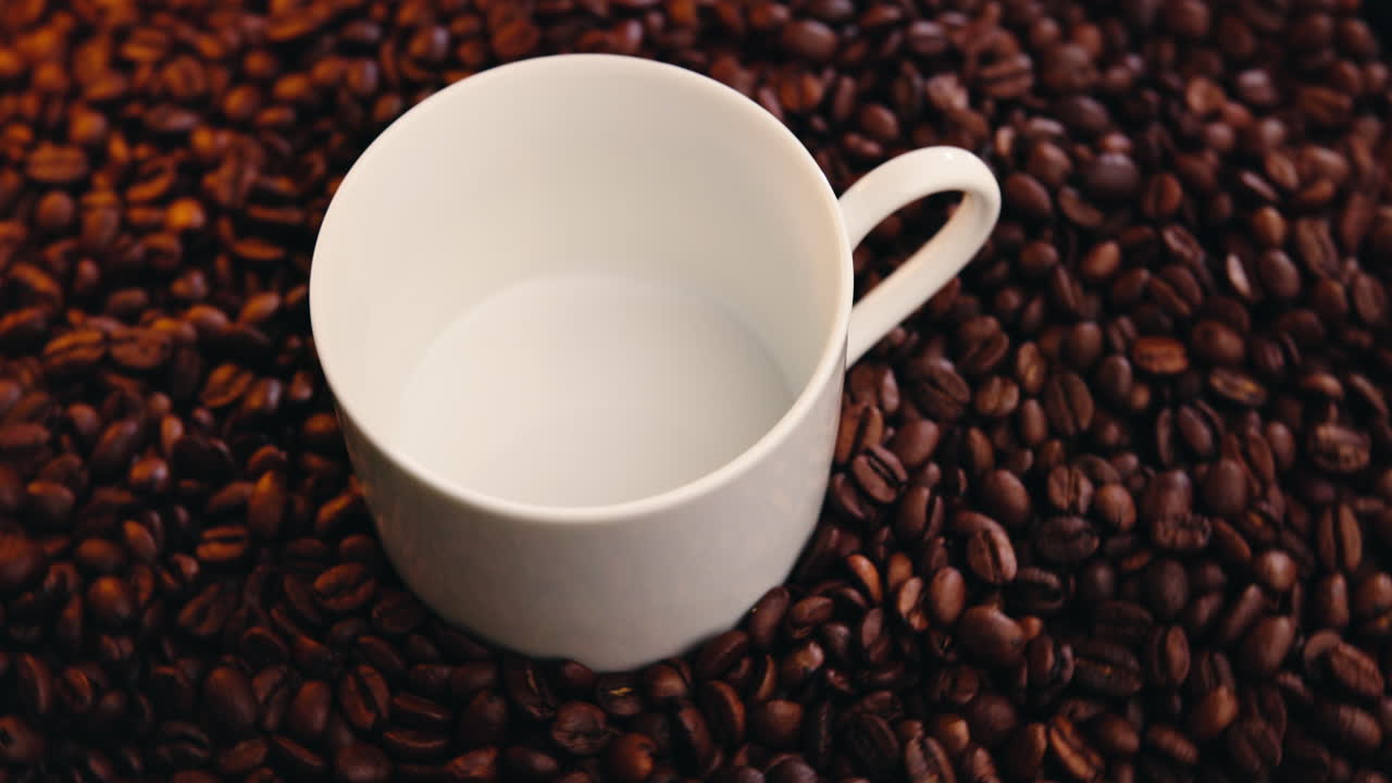 Tazza di caffè bianca su chicchi di caffè tostati rotanti