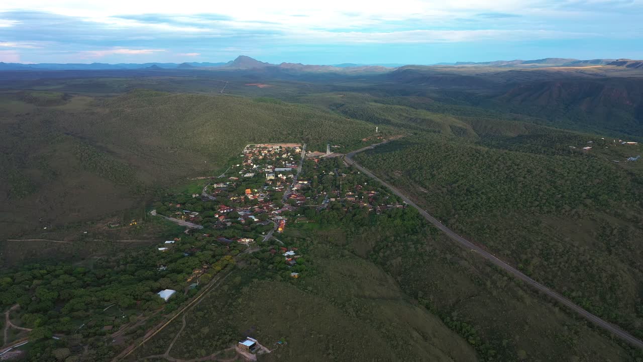 A vista aérea da Vila de São Jorge ao pôr do sol mostra a vila situada em um planalto rico em quartzo, com o Morro da Baleia se elevando no plano de fundo dentro da paisagem da Chapada dos Veadeiros.