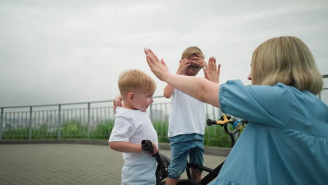 a mother and her two children enjoy a joyful moment outdoors as they enthusiastically give each other high-fives