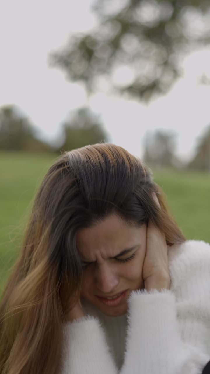 Mulher sofrendo de dor de cabeça, estresse ou barulho alto ao ar livre