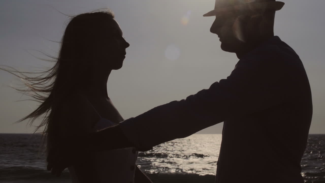 젊은 부부 가 바 ⁇ 가 에서 포옹 하고 키스 하고 있다