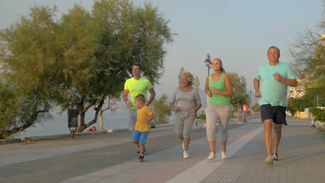 big family running on road next to the sea