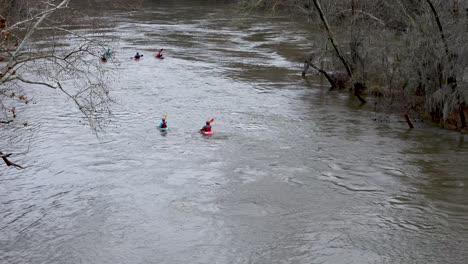 Eine-Gruppe-Von-Kajakfahrern,-Die-Im-Winter-An-Einem-Bewölkten-Tag-Einen-Schlammigen-Fluss-Befahren