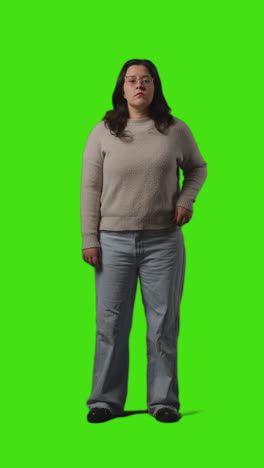 Vertical-Video-Full-Length-Portrait-Shot-Of-Serious-Casually-Dressed-Young-Woman-Standing-Against-Green-Screen