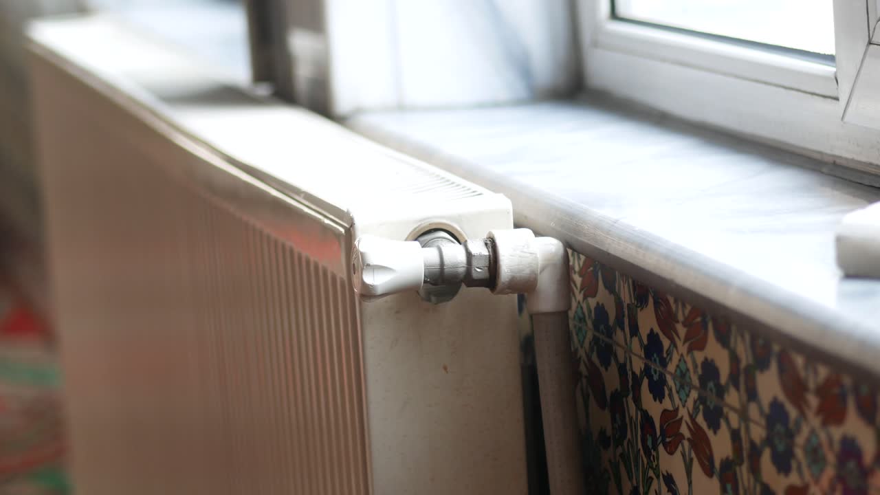Hvid radiator ved vindue med flisedekor