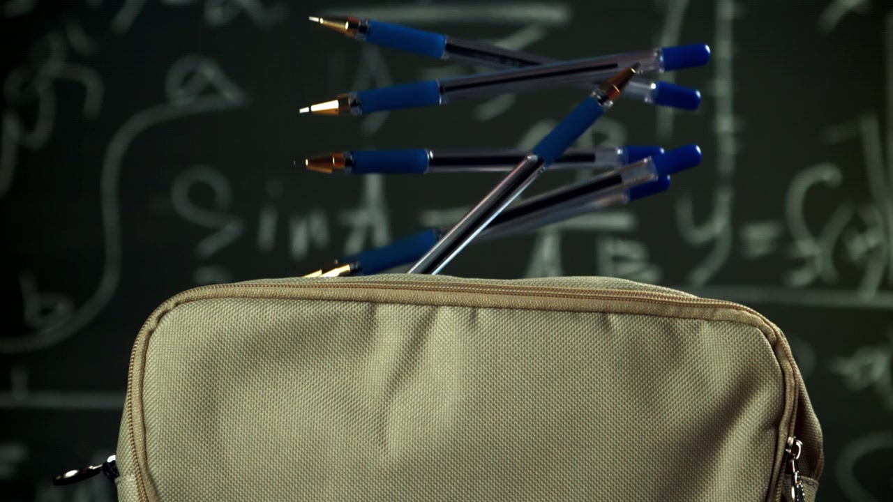 Modrá pera padající do penálu na pozadí matematické tabule