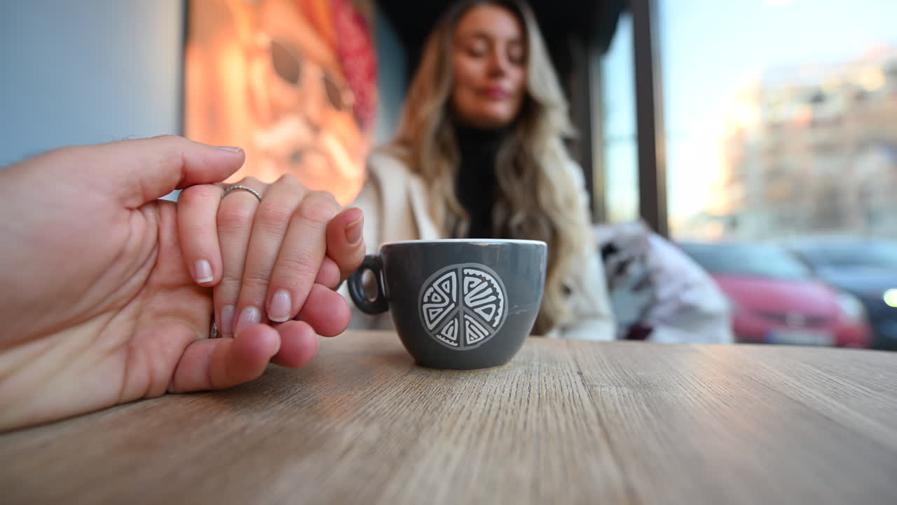 Couple in love holding hands at a restaurant, coffee cup on table