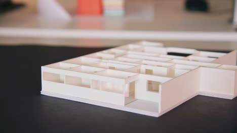 wooden model of building concept sits on architects black desk in office, camera pan