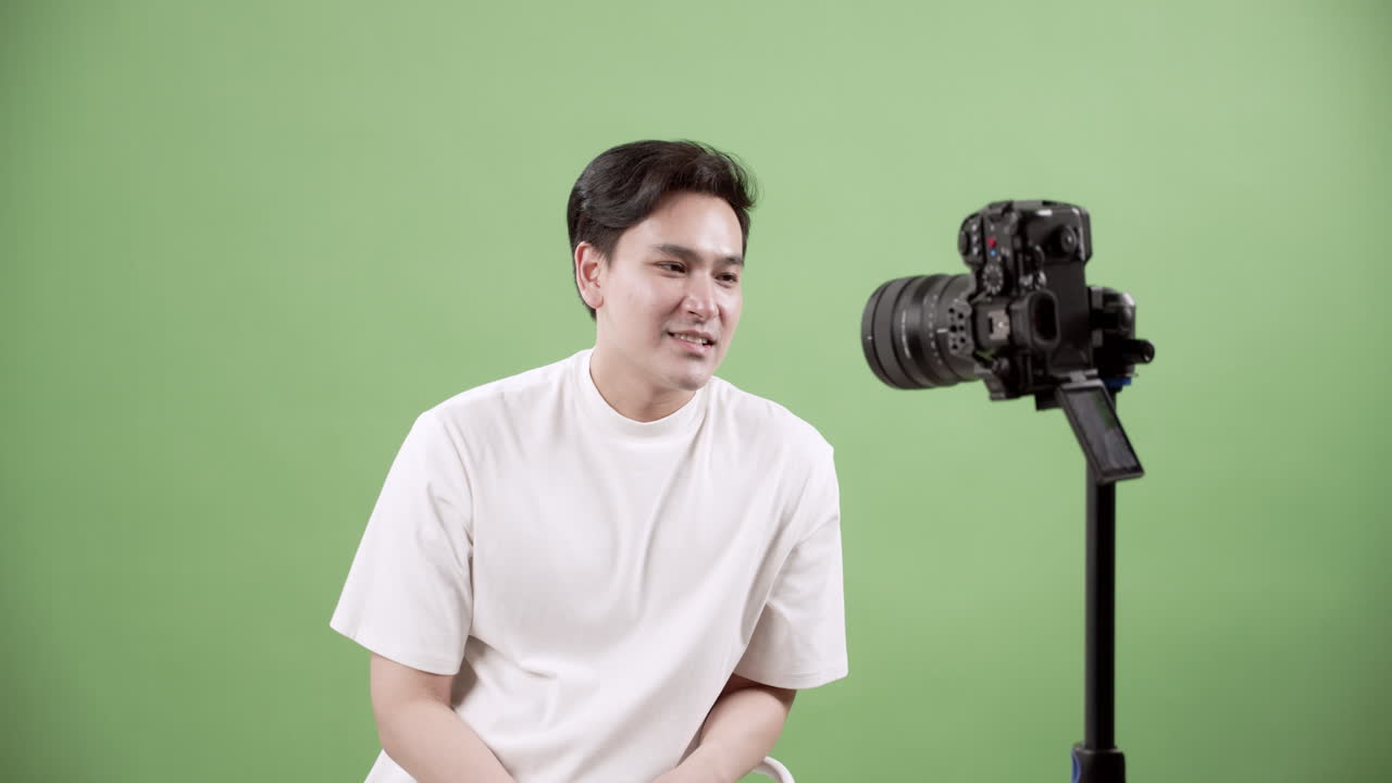 A young male engages in a video shoot against a vibrant green backdrop showcasing creativity and modern content creation.