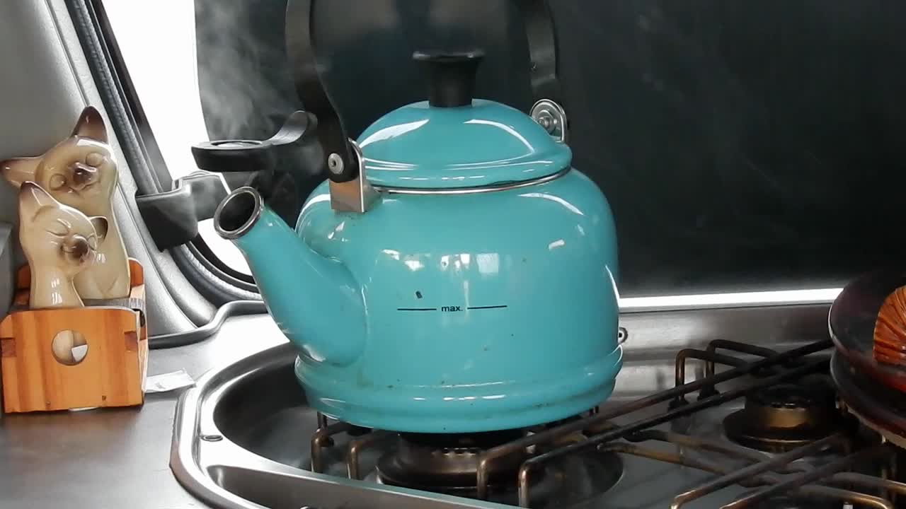 Female hand turning off gas under boiling campervan steam kettle vanlife freedom