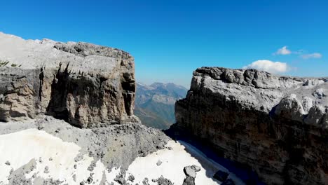 Vuelo-De-Drones-En-Dirección-A-Una-Montaña-Y-Rocas-Con-Vistas-A-Un-Valle-Y-Otras-Montañas