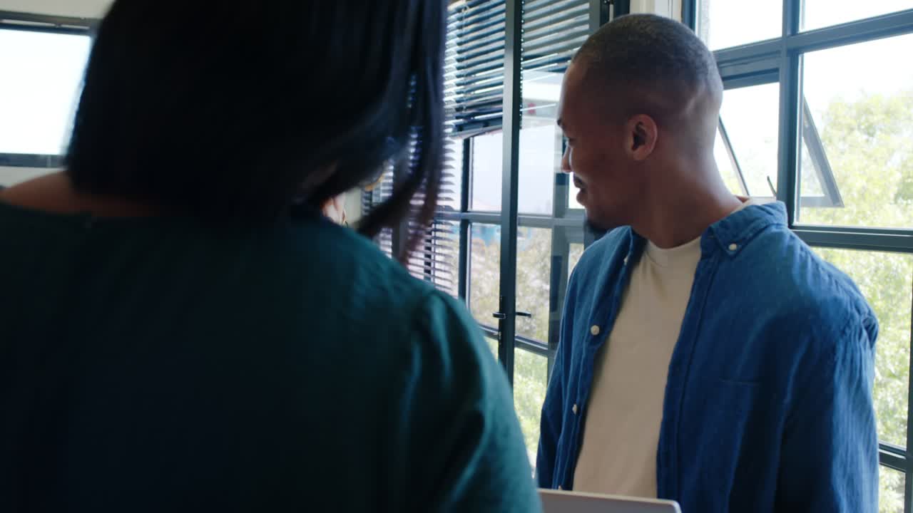 African American colleagues at counter, presenting laptop and papers while consulting receptionist