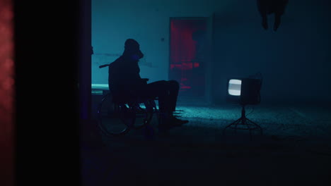 a person in a wheelchair in a neon-lit abandoned room