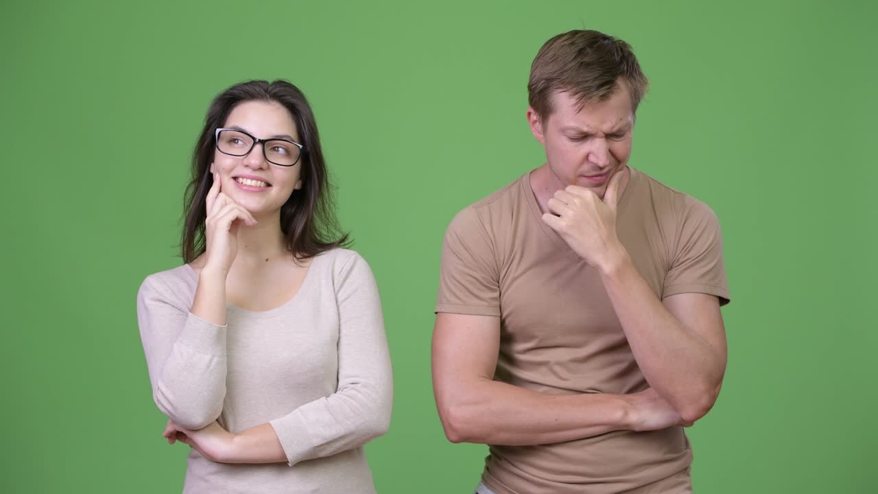 Young couple thinking together against green background