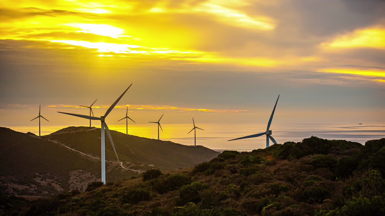 time-lapse de un paisaje nublado naranja sobre una granja de energía eólica en las montañas