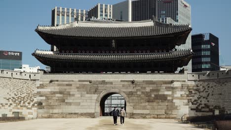 two people wearing protective masks go out from sungnyemun gate seoul, south korea