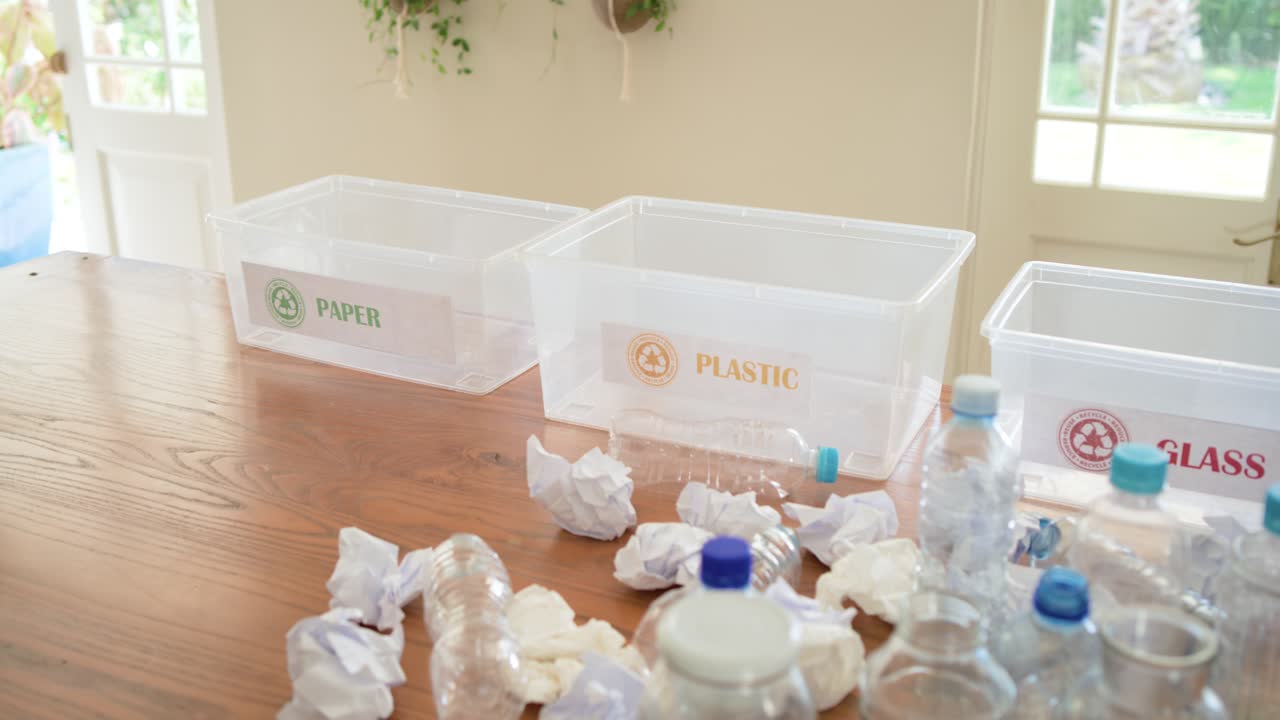 Camera panning right to show glass jars, plastic bottles with blue caps and labeled recycling bins
