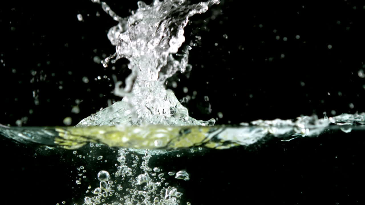 Grapes falling in water on black background
