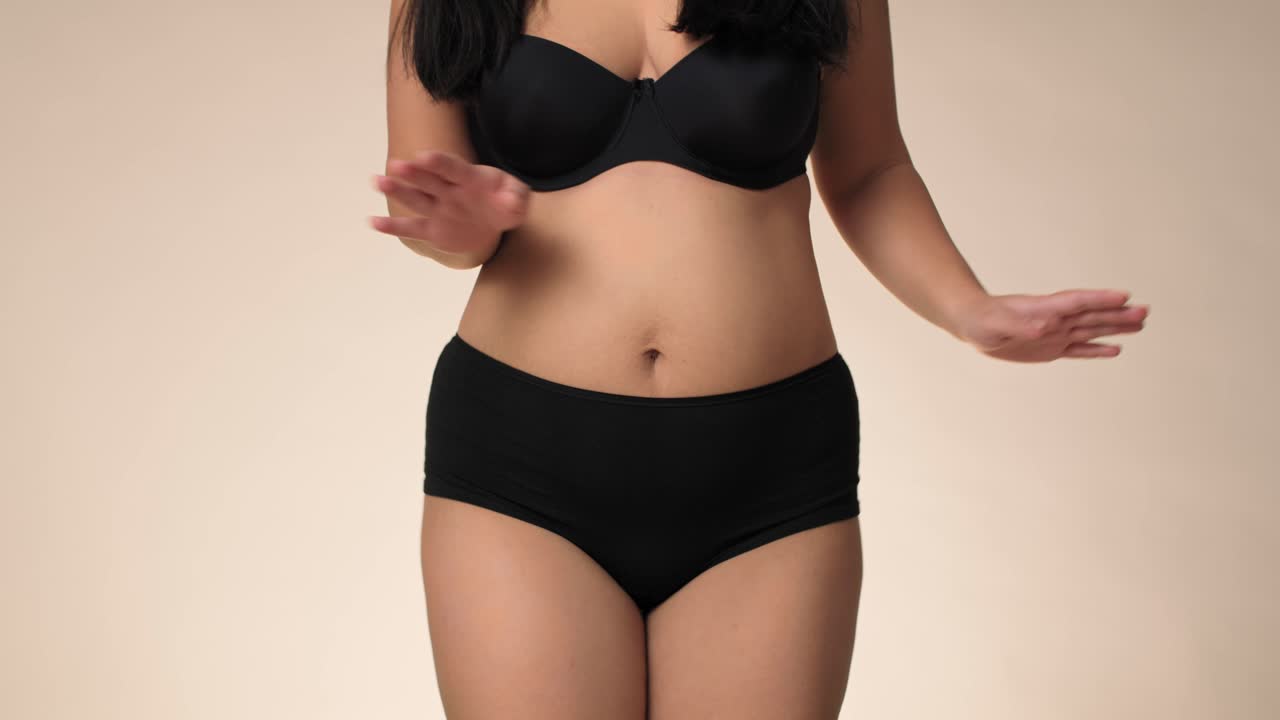 Unrecognizable plus size woman in black underwear dancing in the studio.