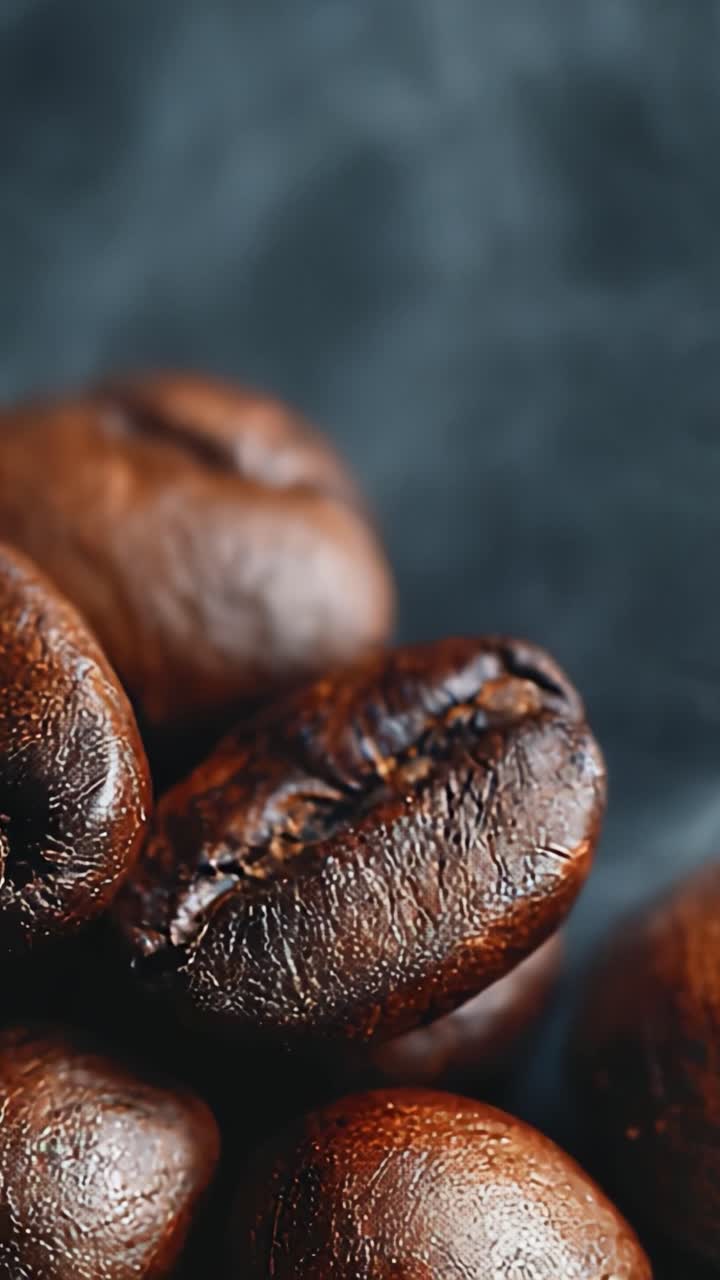 Et nærbillede af ristede kaffebønner med strimler af aromatisk damp, der stiger op, hvilket fanger essensen af friskbrygget kaffe i en kunstnerisk præsentation.