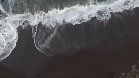 Aerial-view-of-volcanic-beach-cove-seashore-with-black-sand