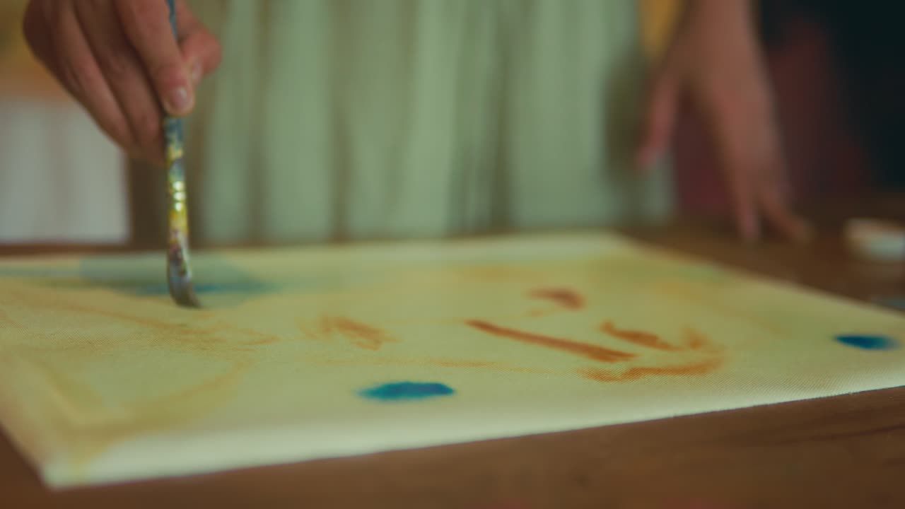 筆と絵の具を使った、紙に描く創造的な屋内アート制作風景の接写。