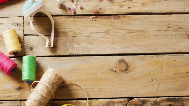 Video of tape measure, pin cushion, threads, fabric and zips on wooden background with copy space