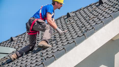 male roofer with safety bell removes roof tiles for solar panel construction